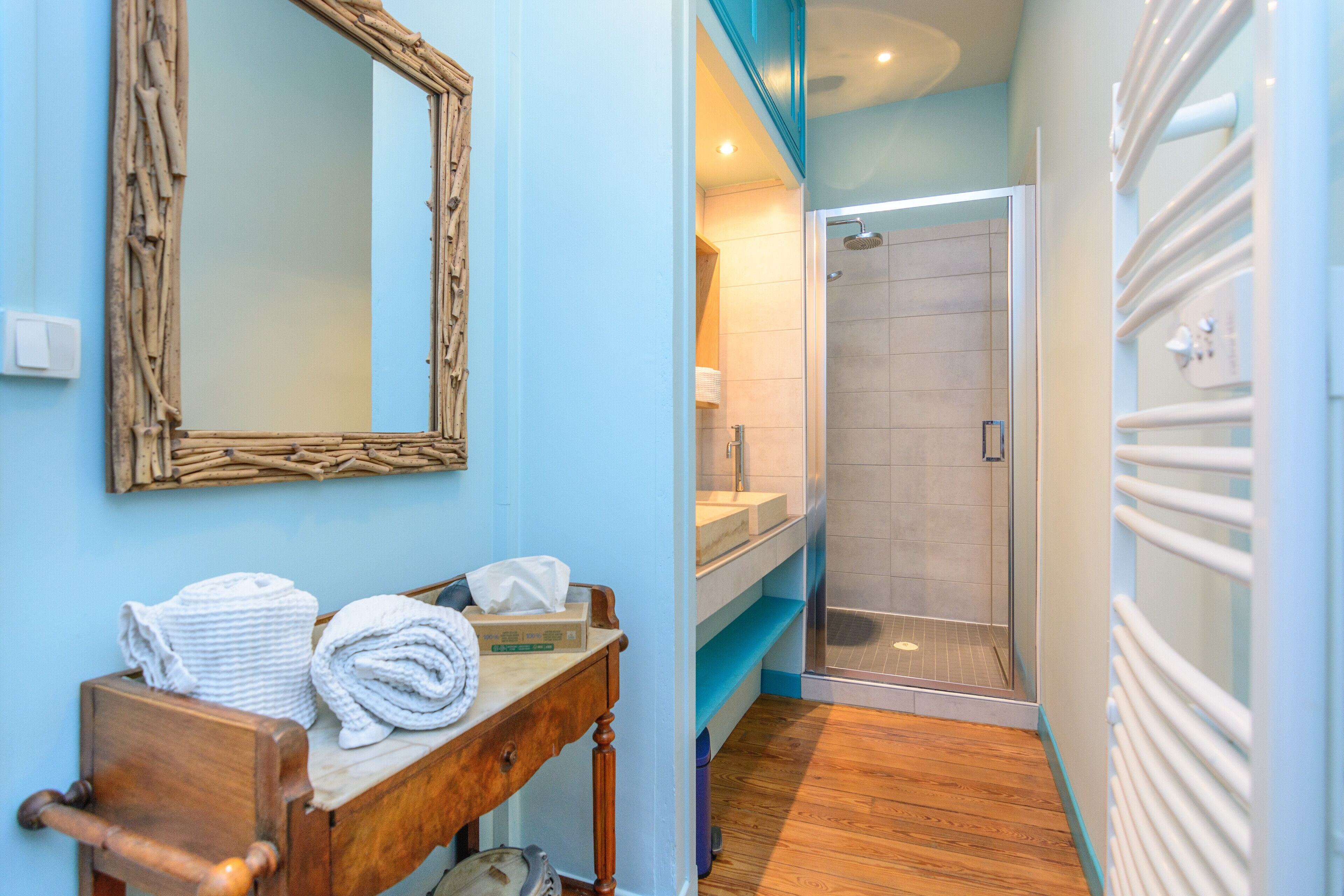 A bathroom with a wooden vanity, a mirror, and a shower area.