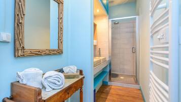 A bathroom with a wooden vanity, a mirror, and a shower area.