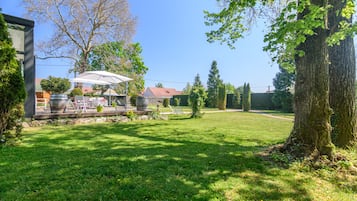 A spacious backyard with a patio area, a large tree, and a well-maintained lawn.