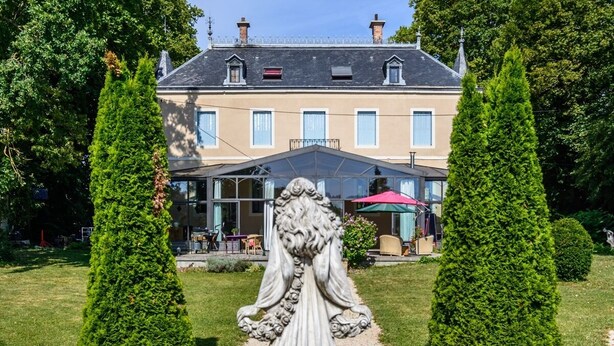 Een beeldschone tuin met een gebouw op de achtergrond en een standbeeld.