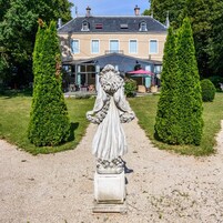 Una estatua en un jardín con un edificio al fondo.
