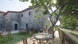 A stone building with a circular glass table and wicker chairs in an outdoor patio area. - Reitoral de Parada (Parada de Sil)