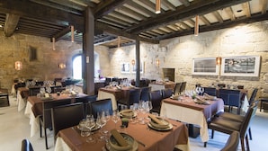 A restaurant with multiple tables set for dining, stone walls, and hanging pendant lights. - Reitoral de Parada (Parada de Sil)