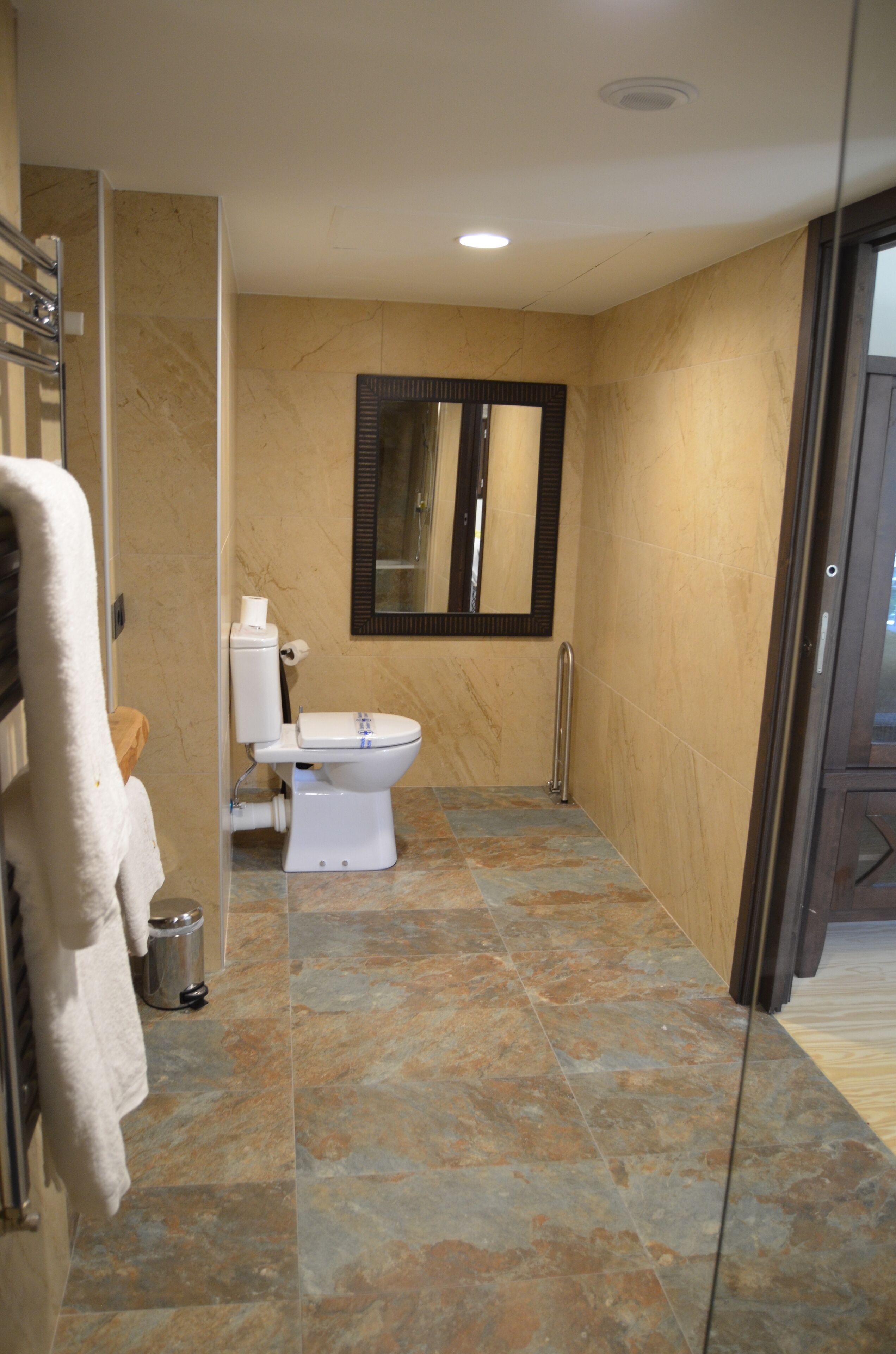 Un baño con inodoro, espejo y zona de ducha.