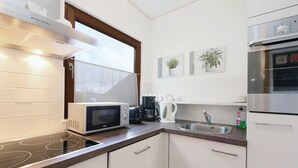 Eine moderne Küche mit weißen Schränken, einer Mikrowelle, einer Kaffeemaschine und einer Spüle aus Edelstahl.