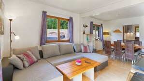 Ein modernes Wohnzimmer mit einer Eckcouch, einem Holztisch und einem Essbereich mit Stühlen und Tisch.