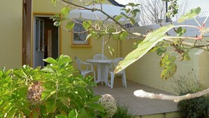 A yellow building with a patio area, white chairs, and a small table. - Attached ground floor apartment on Enclosed grounds (Plouay)