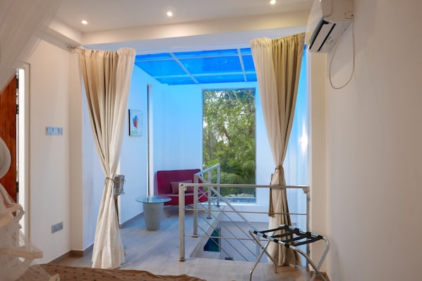 Una habitación con vistas a zonas verdes, un sofá rojo y un tendedero de metal.