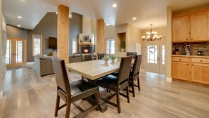 Un comedor amplio con una gran mesa de madera y sillas, una cocina con gabinetes de madera y una chimenea acogedora.
