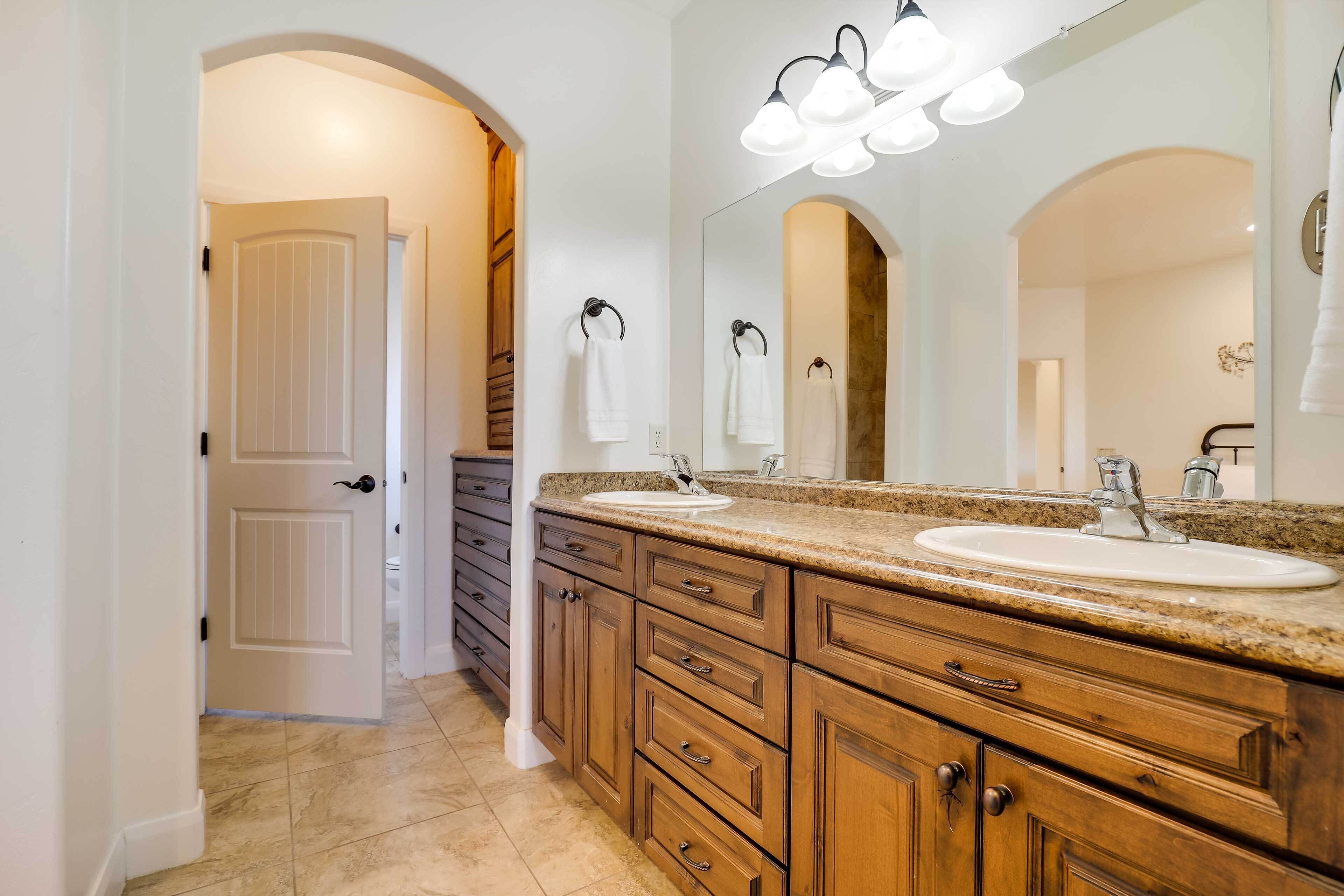 A bathroom with two sinks, wooden cabinets, a large mirror, and a light fixture above the mirror.