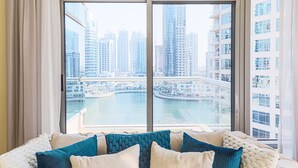 Un salón moderno con un amplio ventanal con vistas a un puerto deportivo y edificios de gran altura.