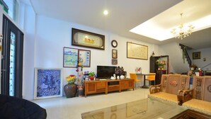 A living room with a glass coffee table, wooden entertainment unit, and traditional furniture. - Happy feet Youth B&B (Hualien City)