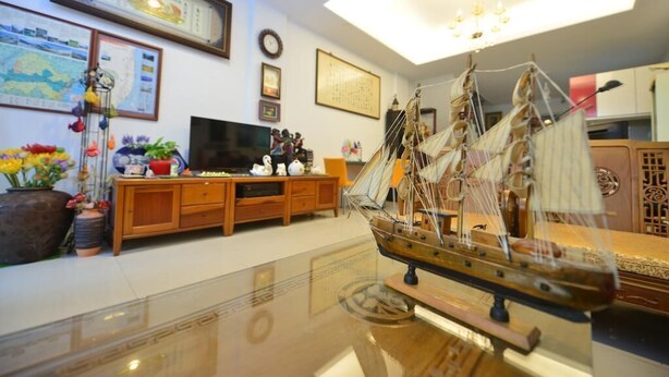 A living room with a wooden cabinet, a television, and a ship model on a glass table. - Happy feet Youth B&B (Hualien City)