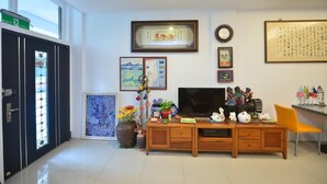 A living room with a TV, wooden cabinet, and various decorations. - Happy feet Youth B&B (Hualien City)
