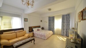 A bedroom with a bed, a sofa, a bench, a dresser, and a chandelier. - Happy feet Youth B&B (Hualien City)