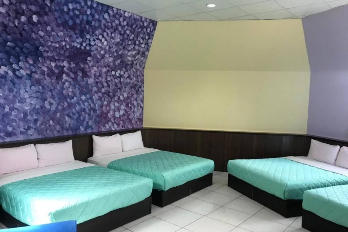 Quarto de hotel com duas camas, um mural grande na parede e piso ladrilhado.