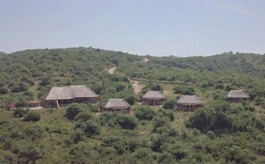 A rural setting with several thatched-roof huts scattered across a hilly landscape.
