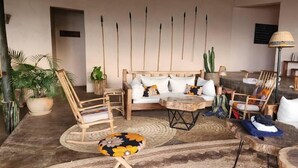 A cozy living room with a sofa, chairs, a coffee table, and a lamp. - Kikonko Lodge (Buseruka)