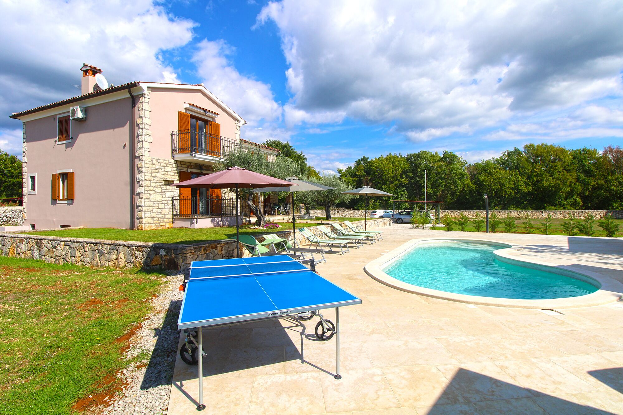 A house with a swimming pool, a ping pong table, and outdoor seating.