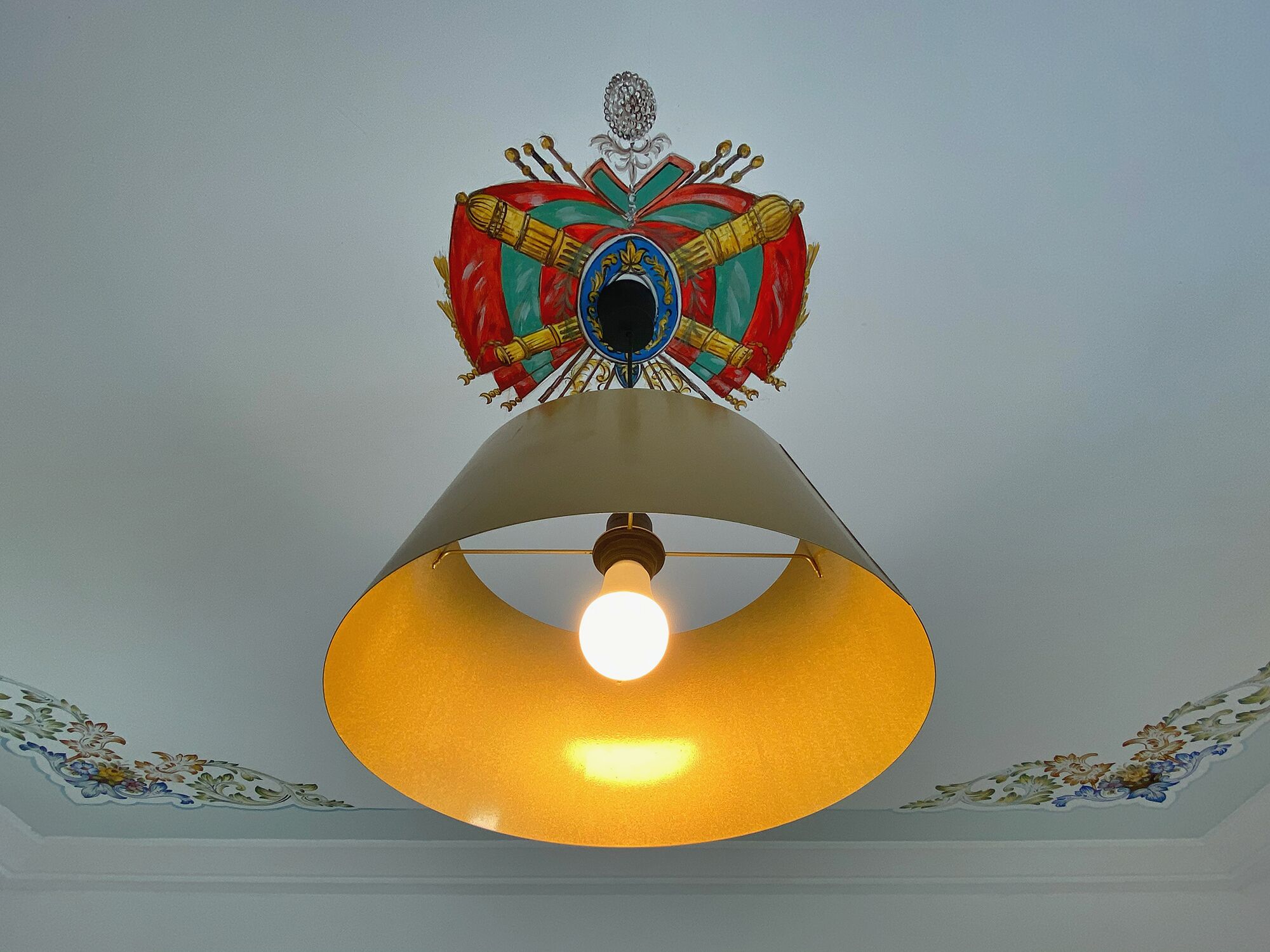 A ceiling with a decorative emblem and a hanging lamp.