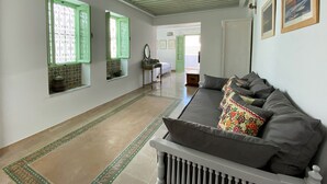 A hallway with a sofa, green-framed windows, and patterned floor tiles. - Dar El Kif La Marsa (La Marsa)