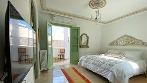 A bedroom with a bed, a television, a radiator, a chair, and a small table. - Dar El Kif La Marsa (La Marsa)
