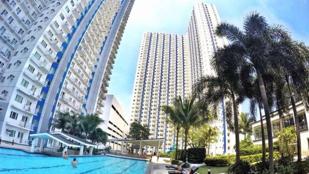 A swimming pool area with high-rise residential buildings in the background. - Grass Residences - Condo (Quezon City)
