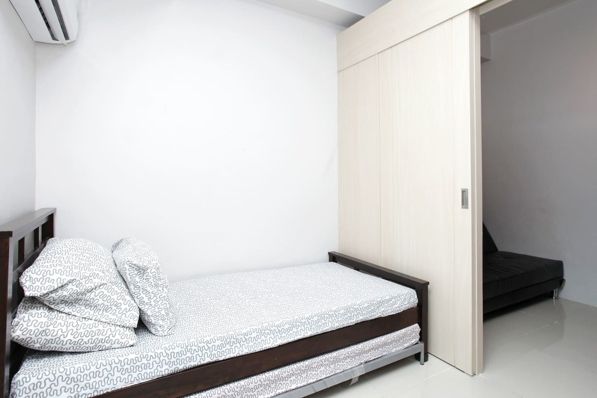 Ein schlicht eingerichtetes Schlafzimmer mit einem Bett, einem Kleiderschrank und einem kleinen Nachttisch.