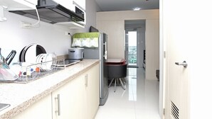 A modern kitchen with a countertop, a stove, and a refrigerator. - Grass Residences - Condo (Quezon City)