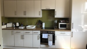 Een moderne keuken met witte kasten, een magnetron, een broodrooster en een vaatwasser.