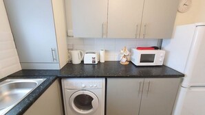 A compact kitchen with a washing machine, a microwave, a toaster, and a sink.