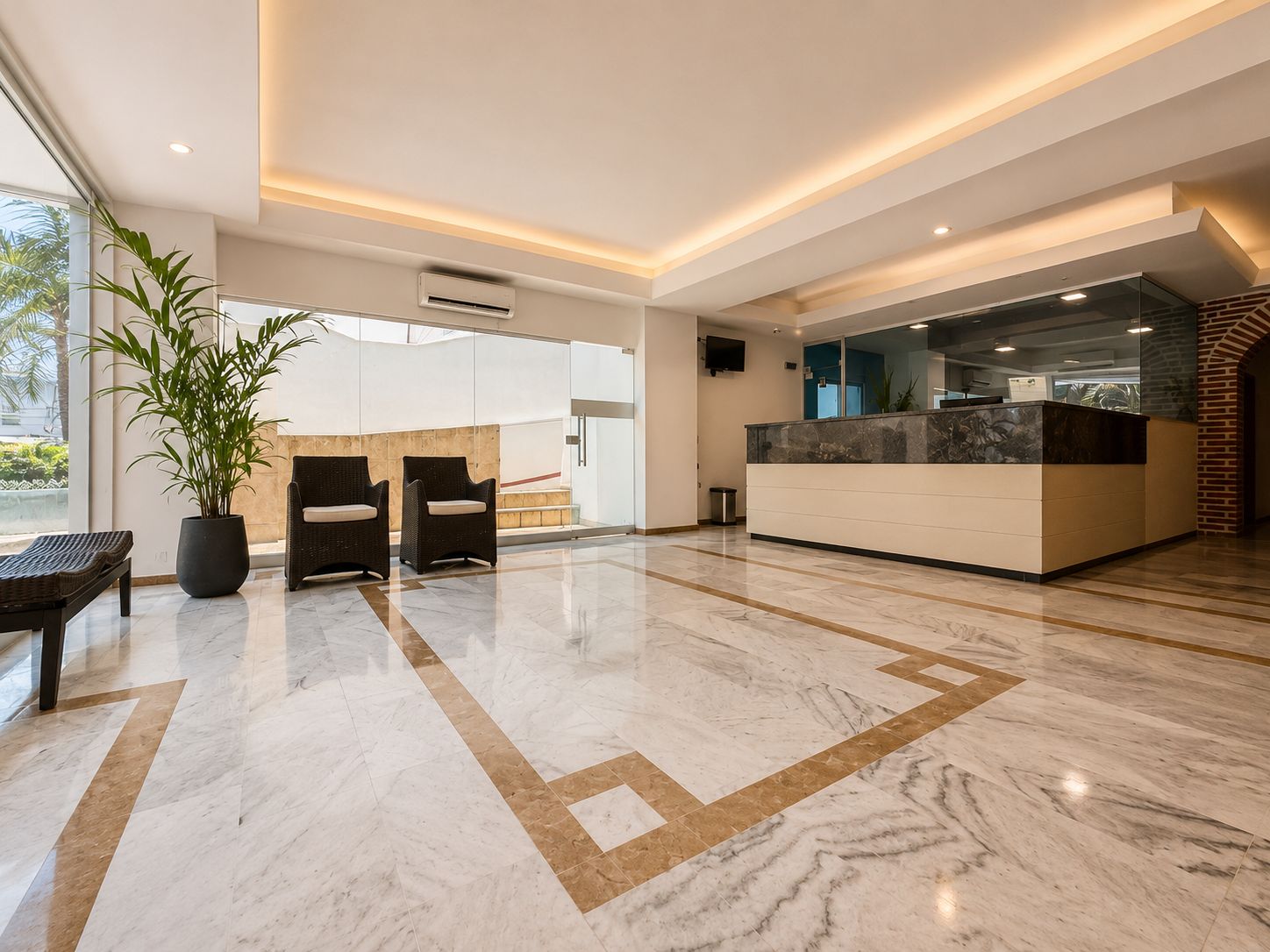 A modern lobby with a reception desk, seating area, and a large potted plant.