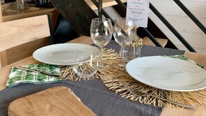 A dining table set with plates, cutlery, and wine glasses, with a menu sign on the table. - Bed & Breakfast Les Tignoliers (Tignieu-Jameyzieu)