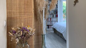 A room with a wicker partition, a glass vase with dried flowers, and a bookshelf in the background. - Bed & Breakfast Les Tignoliers (Tignieu-Jameyzieu)
