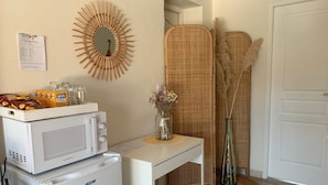 A kitchenette with a white refrigerator, a microwave, and a small table with snacks and a menu. - Bed & Breakfast Les Tignoliers (Tignieu-Jameyzieu)