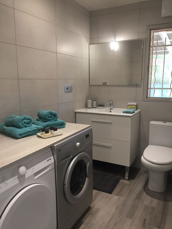 Un baño moderno con lavadora, inodoro y lavabo.