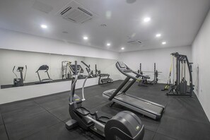 Un gimnasio con cintas de correr, elípticas y equipo de levantamiento de pesas.