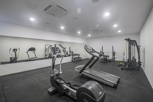 A gym with treadmills, elliptical machines, and weightlifting equipment. - Bohemian Gardens Hotel (Paralimni)