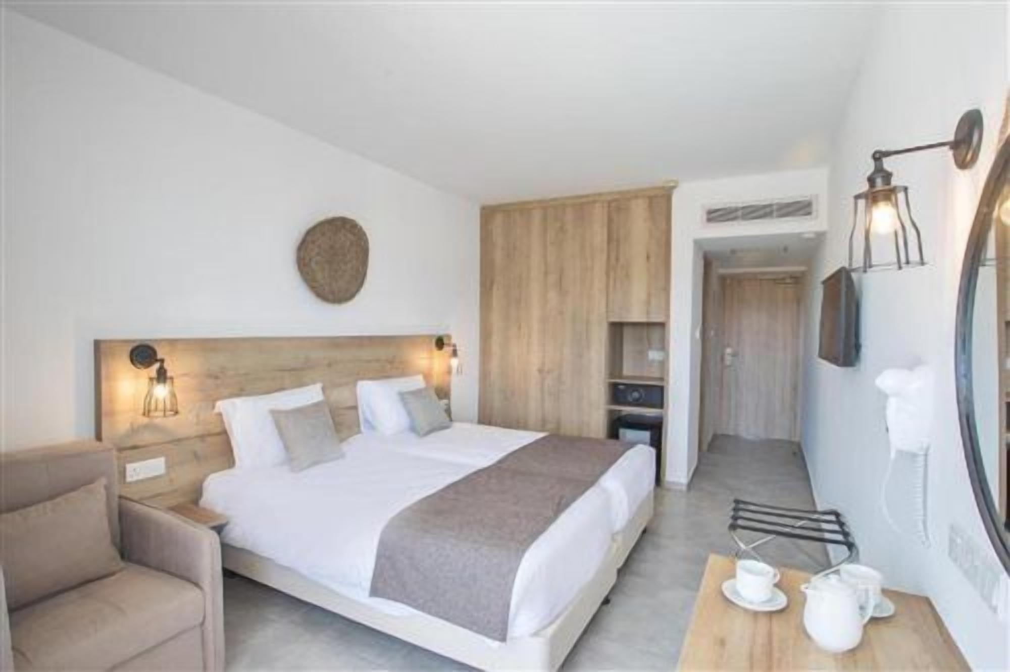 A hotel room with a bed, bedside table, lamp, and a small seating area.