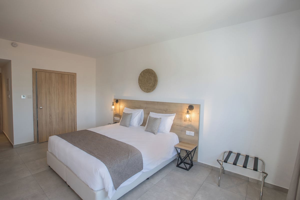 A modern bedroom with a large bed, bedside tables, a bench, and a round wall decoration.