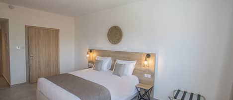 A modern bedroom with a large bed, bedside tables, a bench, and a round wall decoration.