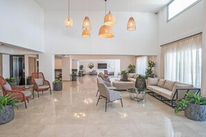 A spacious lobby with a high ceiling, multiple seating areas, and a central coffee table. - Bohemian Gardens Hotel (Paralimni)