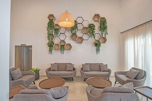 Una sala de estar moderna con estanterías hexagonales en la pared, sofás grises, mesas de centro de madera redondas y una lámpara colgante.