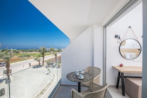 A balcony with a table, chairs, a small table with a red apple, and a hanging mirror. - Bohemian Gardens Hotel (Paralimni)