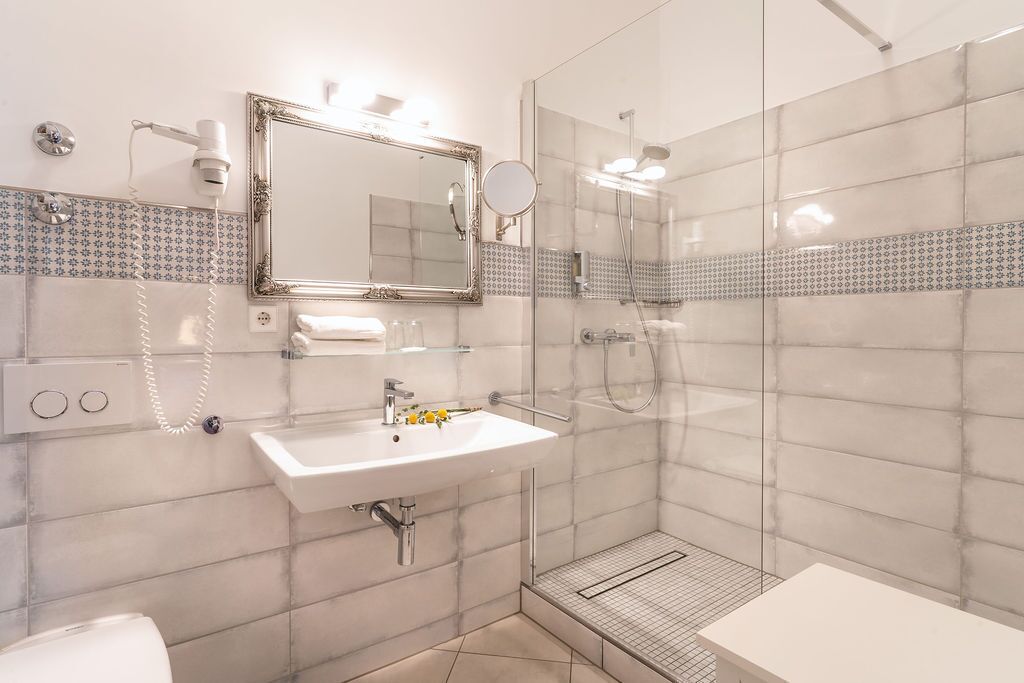 A modern bathroom with a glass shower enclosure, a white sink, and a large mirror.