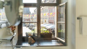 A kitchen with a large window overlooking a street with buildings and flags. - Pirn'scher Hof - Hotel Garni (Pirna)