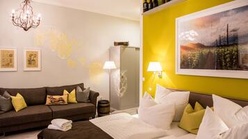 Ein Hotelzimmer mit Bett, einer Couch, einem Chandelier, Wandbildern und einem Weinschrank.