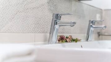 Un baño moderno con un lavamanos blanco y dos grifos cromados.