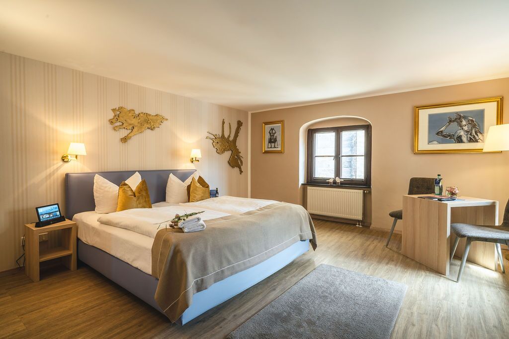 A modern hotel room with a large bed, a desk, and a window with a view.