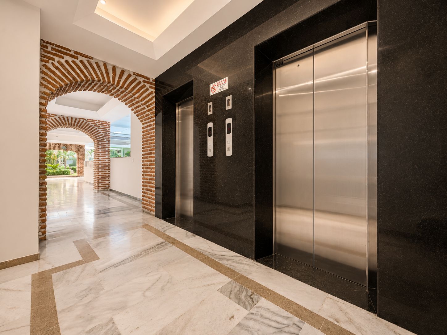 Et moderne elevatorområde med en marmorgulv og en murstensbue.